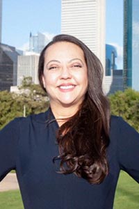 Real estate agent Lucy Petry, smiling warmly, standing in front of a suburban home, representing Hall & Sirs Realty