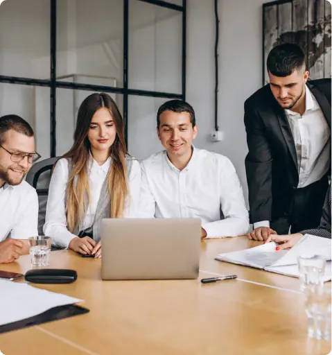 Professionals in a meeting room with a laptop and documents on the table.