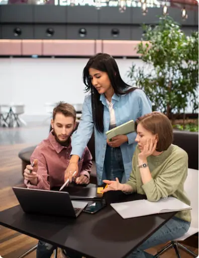 Three individuals collaborating over a laptop in a modern office space.